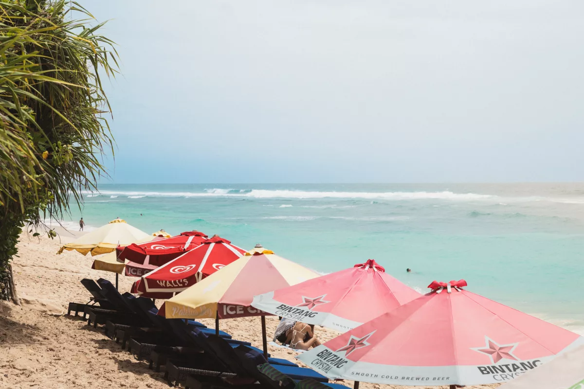 Liegen und Sonnenschirme an einem Strand vor türkisblauem Meer