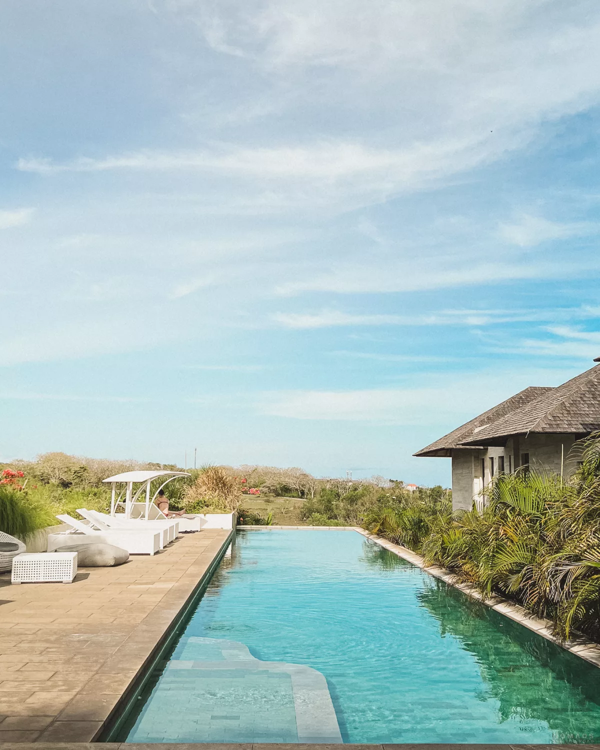 Blick auf einen Pool mit Liegen auf der Terrasse in einem Surfcamp