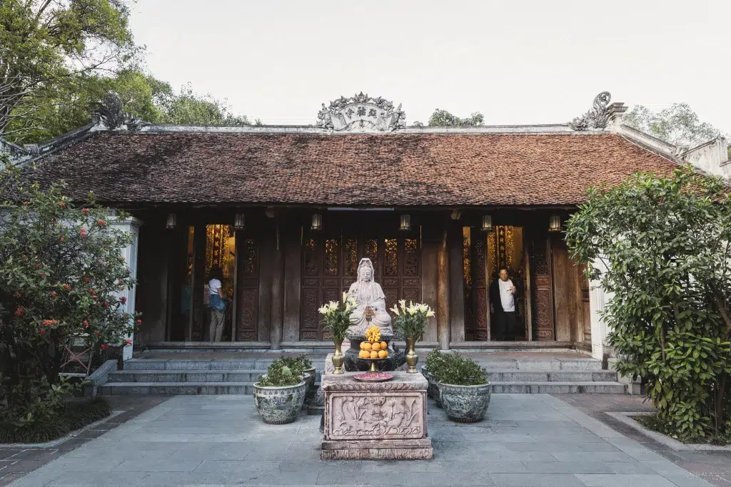 Buddha Statue mit Opfergaben vor dem Dien Huu Temple in Hanoi