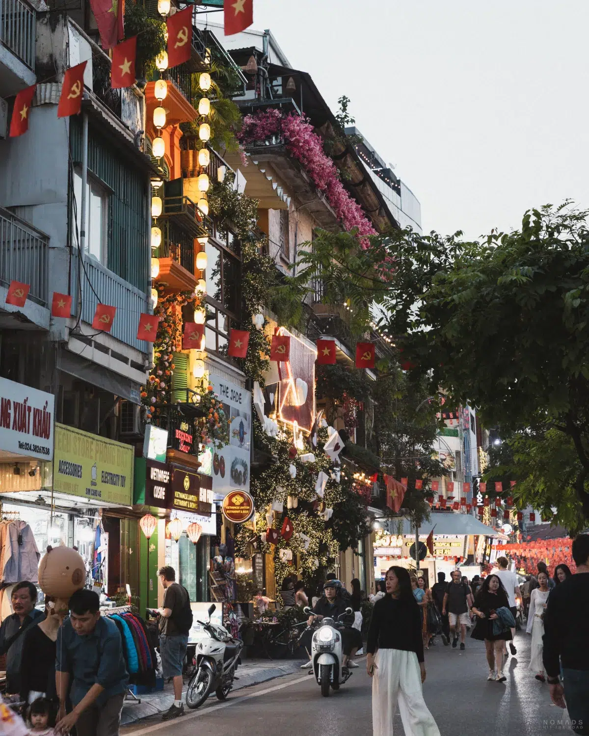 Gebäude und Straße auf denen Menschen laufen im Old Quarter von Hanoi