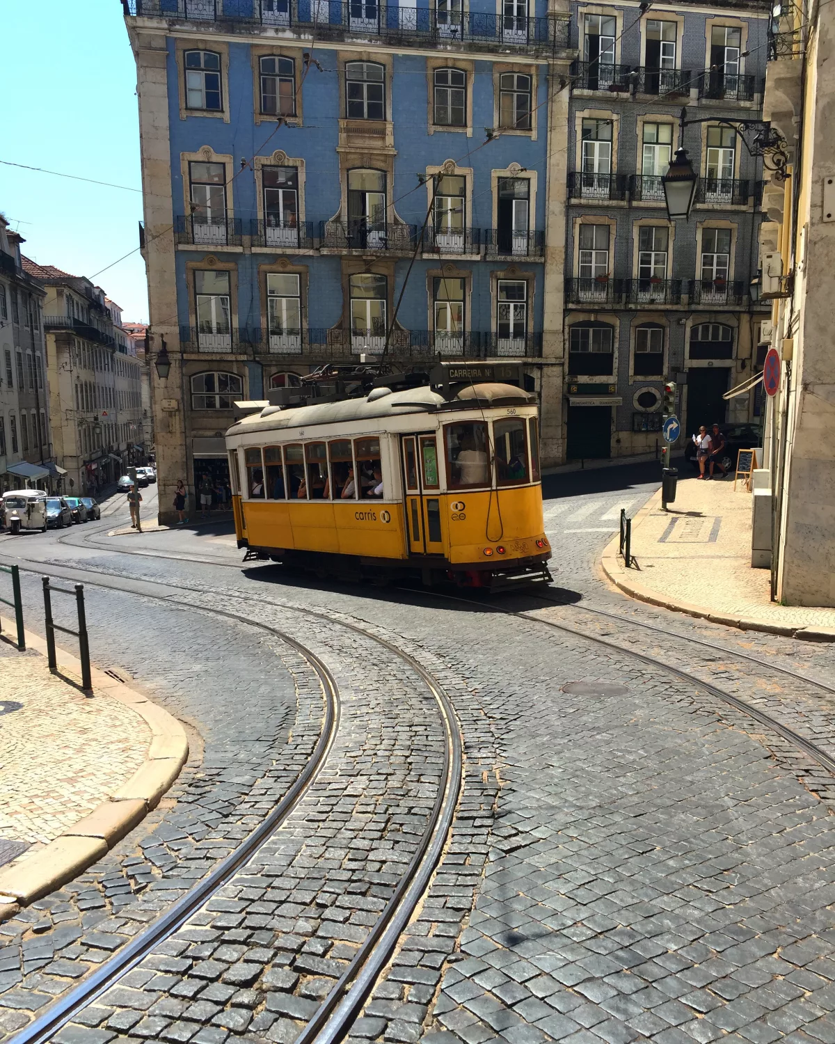 Gelbe Straßenbahn fährt an einer Straße in Lissabon entlang