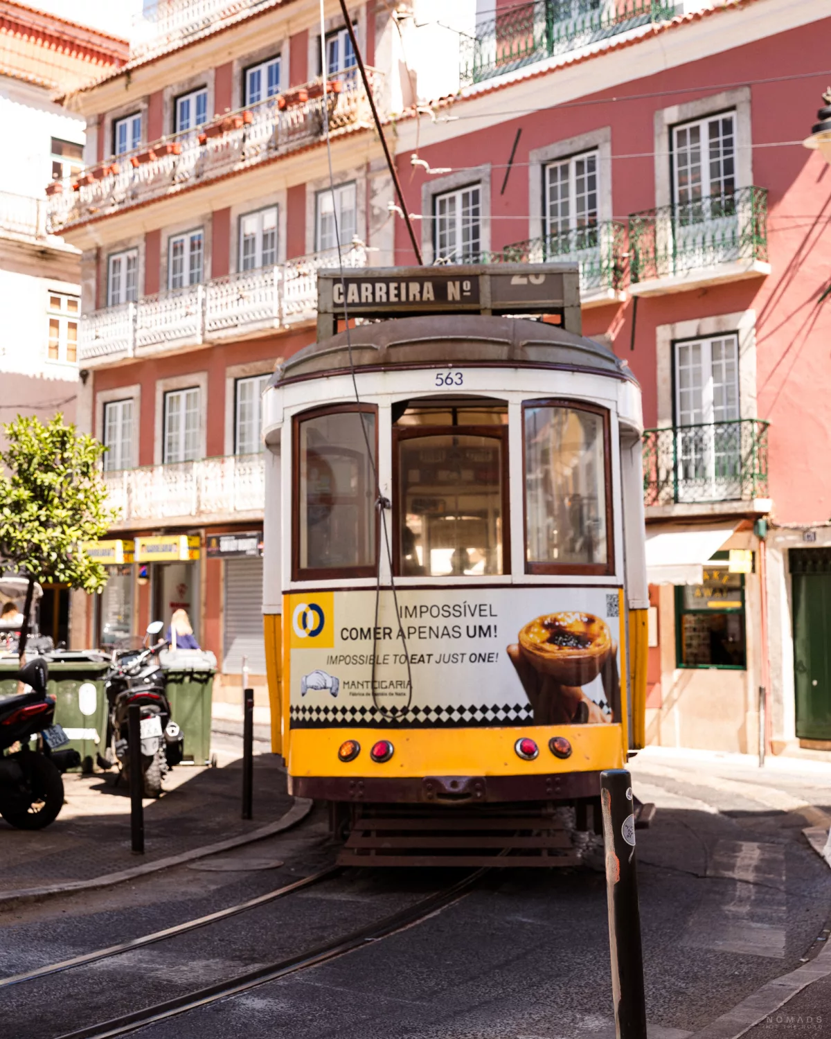 Gelbe Tram vor einem pinken Haus in Lissabon