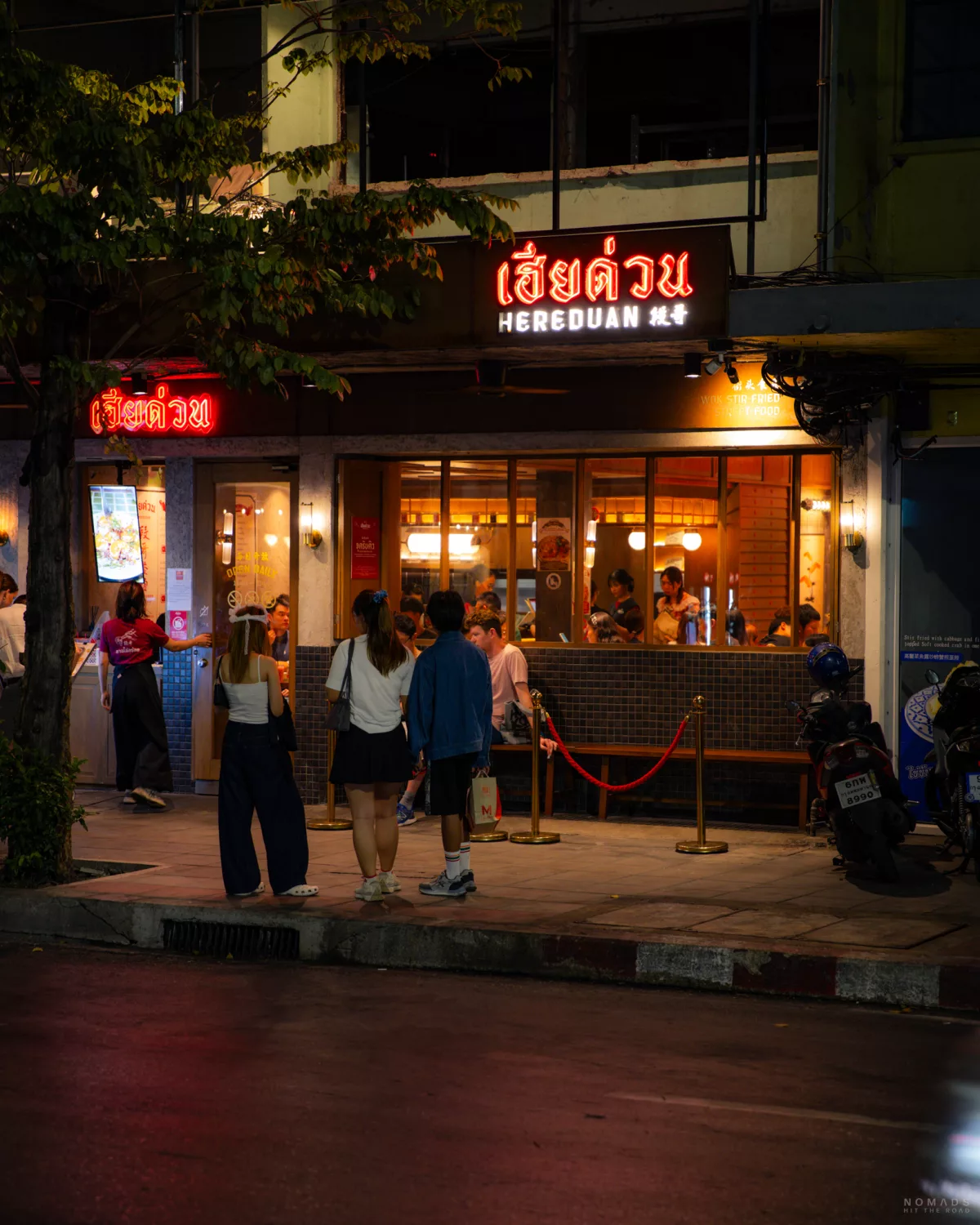 Menschen warten abends vor dem Restaurant Here Duan auf der Banthat Thong Road
