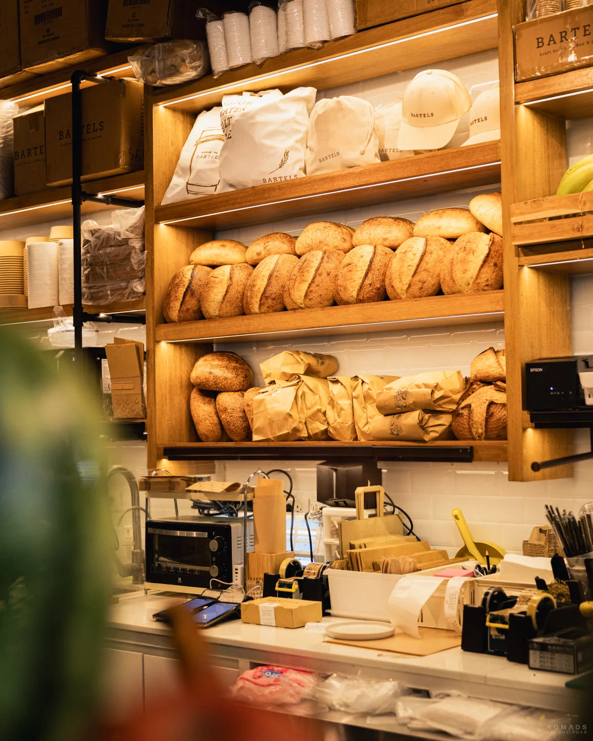 Brot aufgereiht in einem Regal sowie vollgestellte Theke im Bartels in Bangkok
