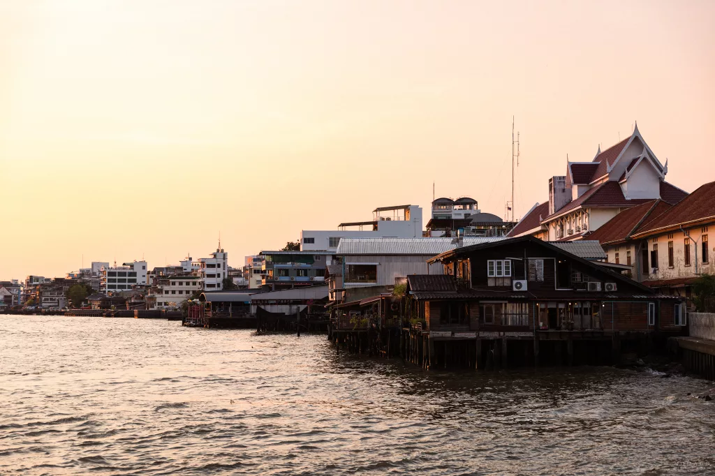 Häuser am Ufer des Chao Praya bei Sonnenuntergang