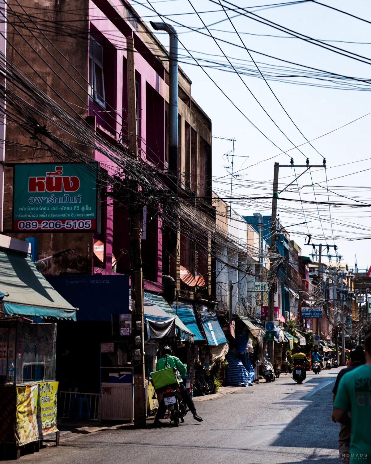 Straße mit Geschäften, Rollern und viele Stromkabel in Bang Phlat, Bangkok