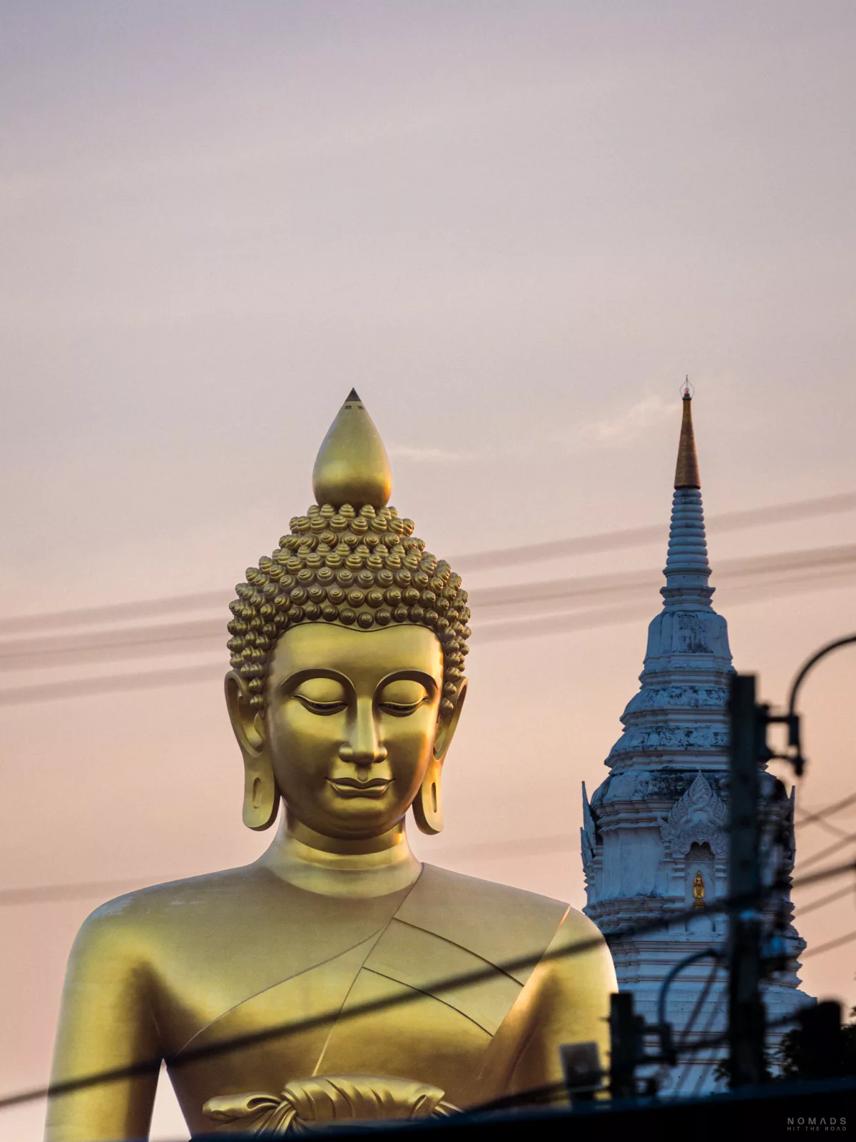 Blick auf den goldenen riesigen Big Buddha in Bangkok mit Tempel im Hintergrund bei Sonnenuntergang
