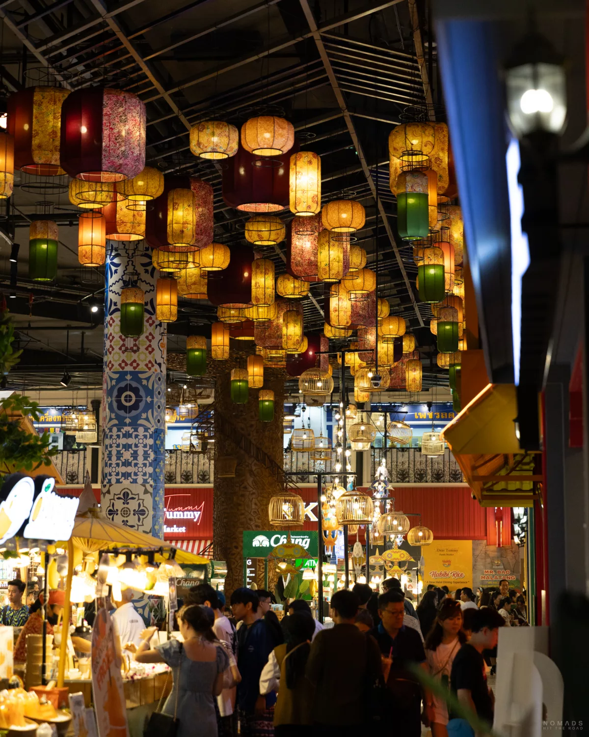 Bunte Lampen hängen im Foodcourt der Icon Siam Mall während Menschen an den Foodständen entlang laufen