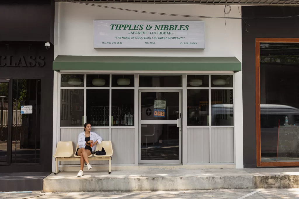 Frau sitzt vor dem Restaurant Tipples & Nibbles in Bangkok