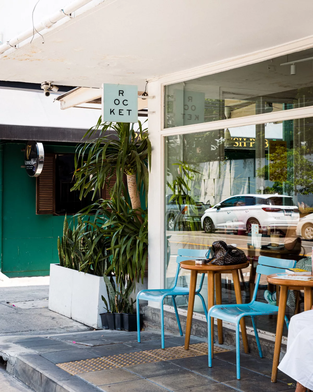 Blaue Stühle und Holztische vor dem Café Rocket in Sathorn, Bangkok