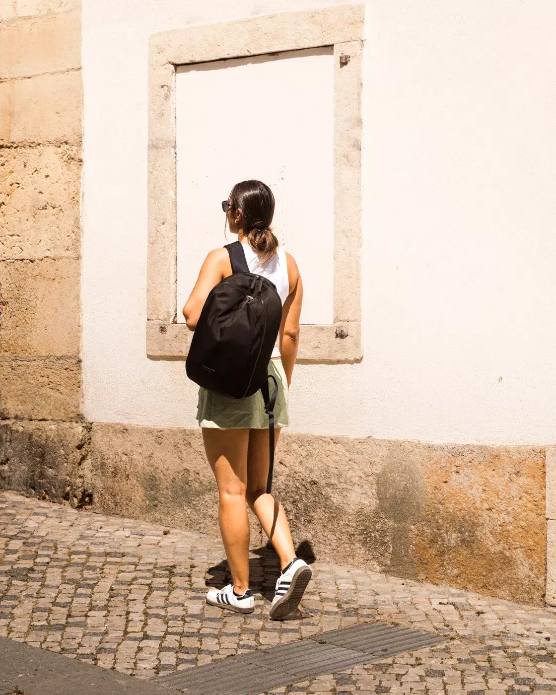 Frau läuft durch eine sonnige Straße mit ihrem Level8 Rucksack
