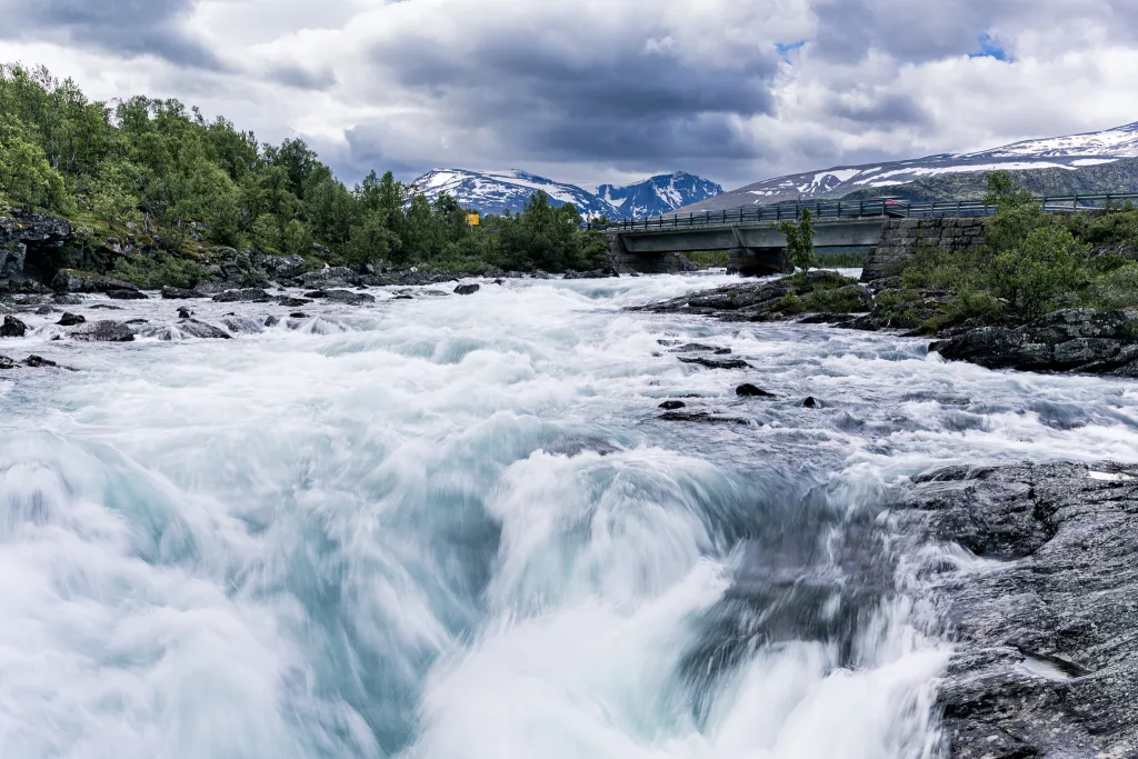 Flusslauf im Jotunheimen Nationalpark mit Blick auf die Berge und Bäumen am Flussufer