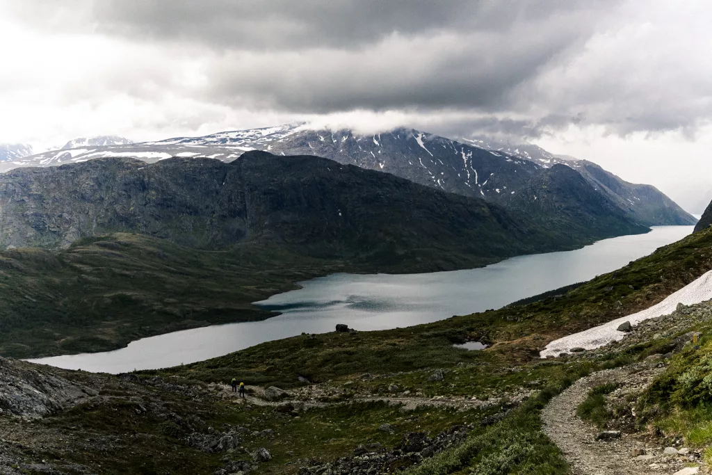Blick auf den Gjende während des Aufstiegs der Besseggen-Wanderung mit Blick auf Berge sowie Schnee am Hang