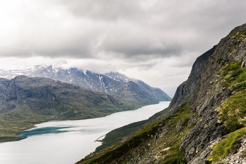 Blick auf den Gjende von einem Berg mit Blick auf Berge sowie einer aufziehenden Regenwolke