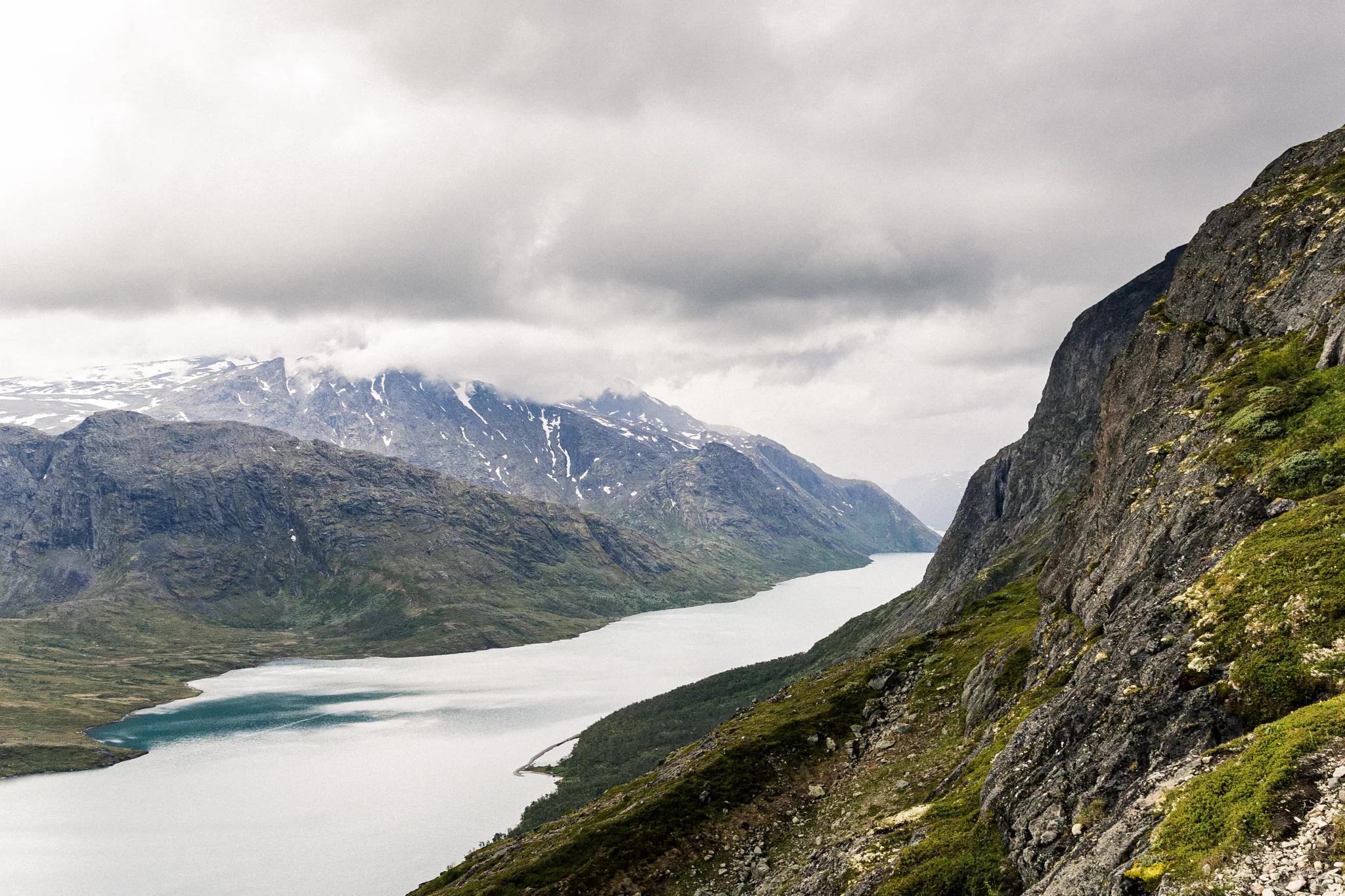 Blick auf den Gjende von einem Berg mit Blick auf Berge sowie einer aufziehenden Regenwolke