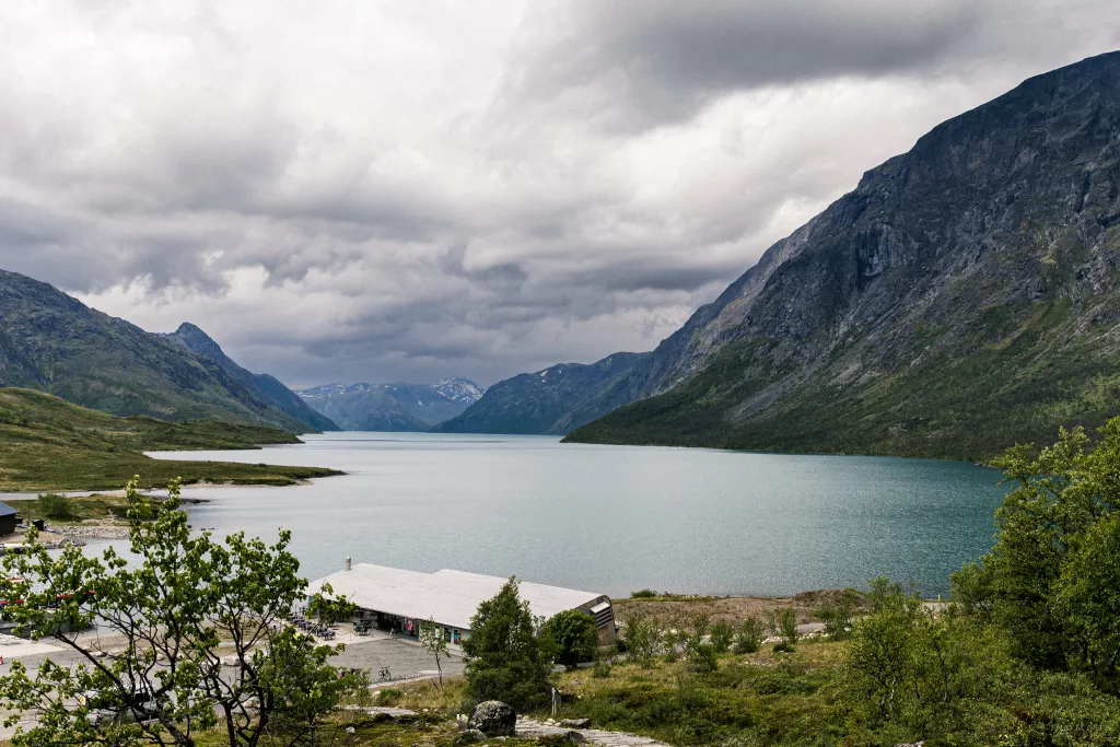 Blick auf den Gjende See und den umliegenden Bergen vom Anleger in Gjendesheim mit dem Cafße am Ufer