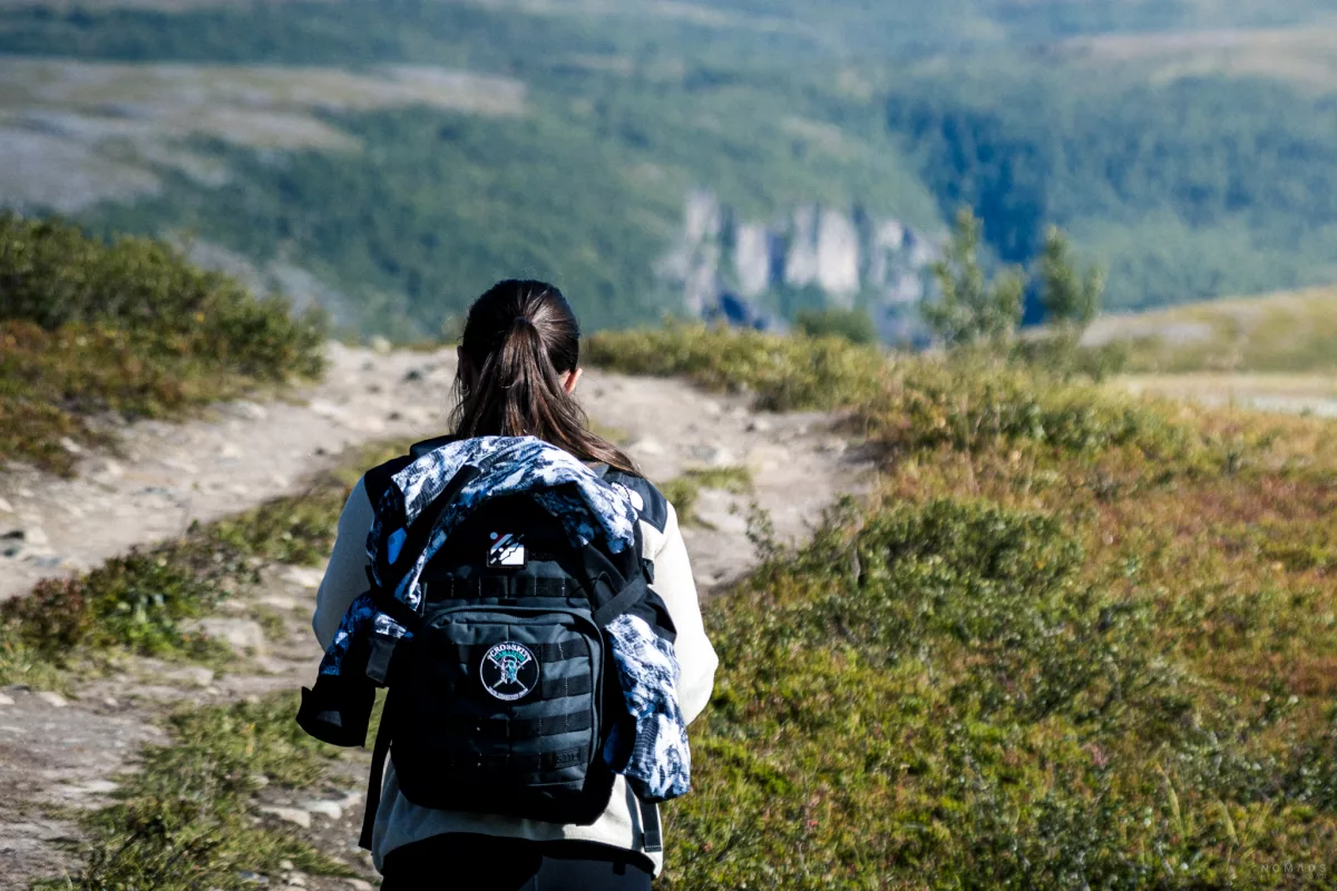 Frau läuft mit einem Rucksack auf einem Wanderweg in Alta