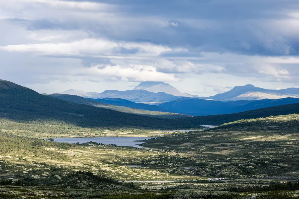 Blick auf die weite Ebene des Dovrefjell Nationalpark mit Bergen, Seen und Wolken am Himmel