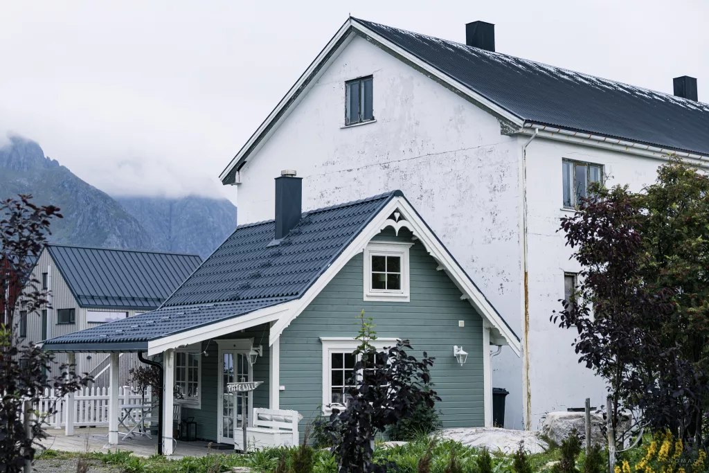 Kleines grünes Airbnb vor einem größeren weißen Haus