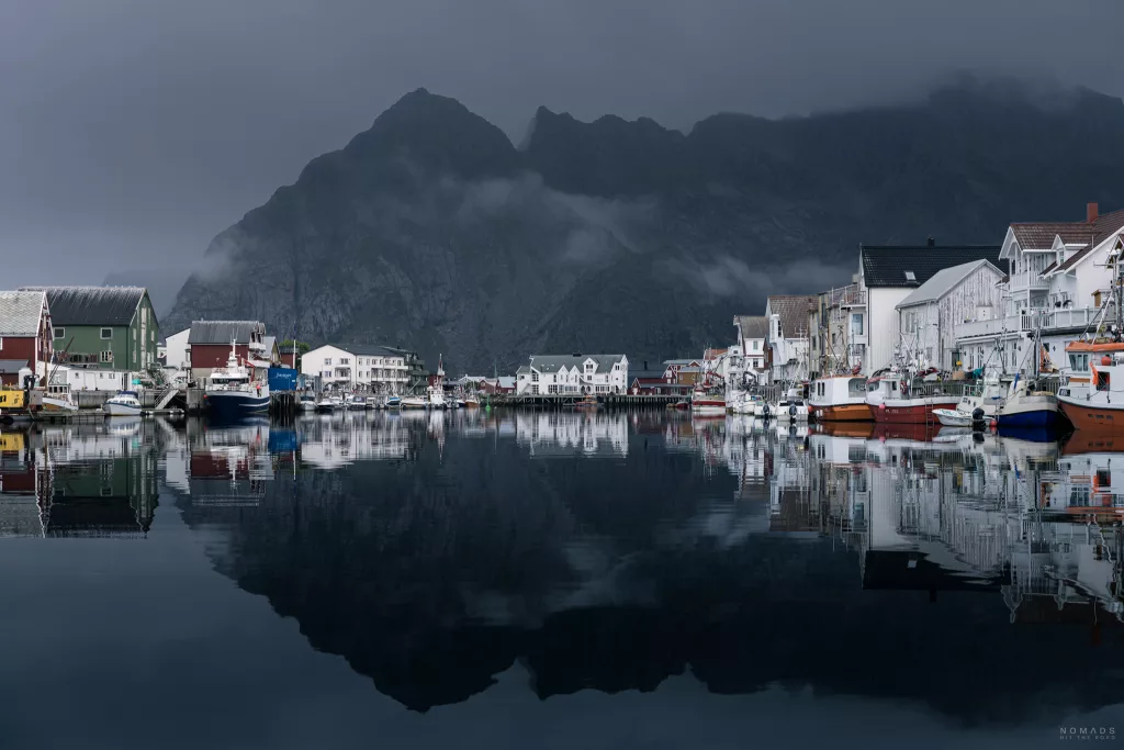 Blick auf den Hafen in dem sich Häuser, Berge und Boote spiegeln