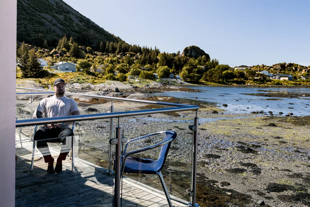 Mann sitzt auf dem Balkon des Lovund Hotells
