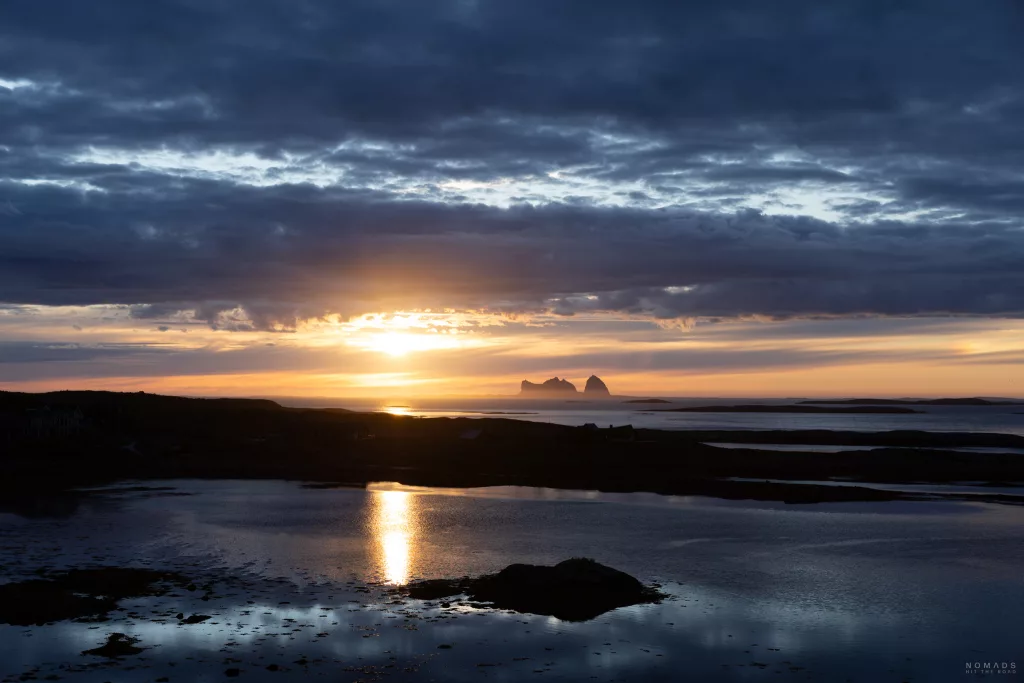 Sonnenuntergang über dem Meer mit Spiegelung im Fjord und Insel im Hintergrund