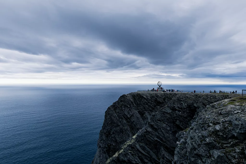 Blick auf den Globus am Nordkap auf einer Klippe mit Menschen drumherum