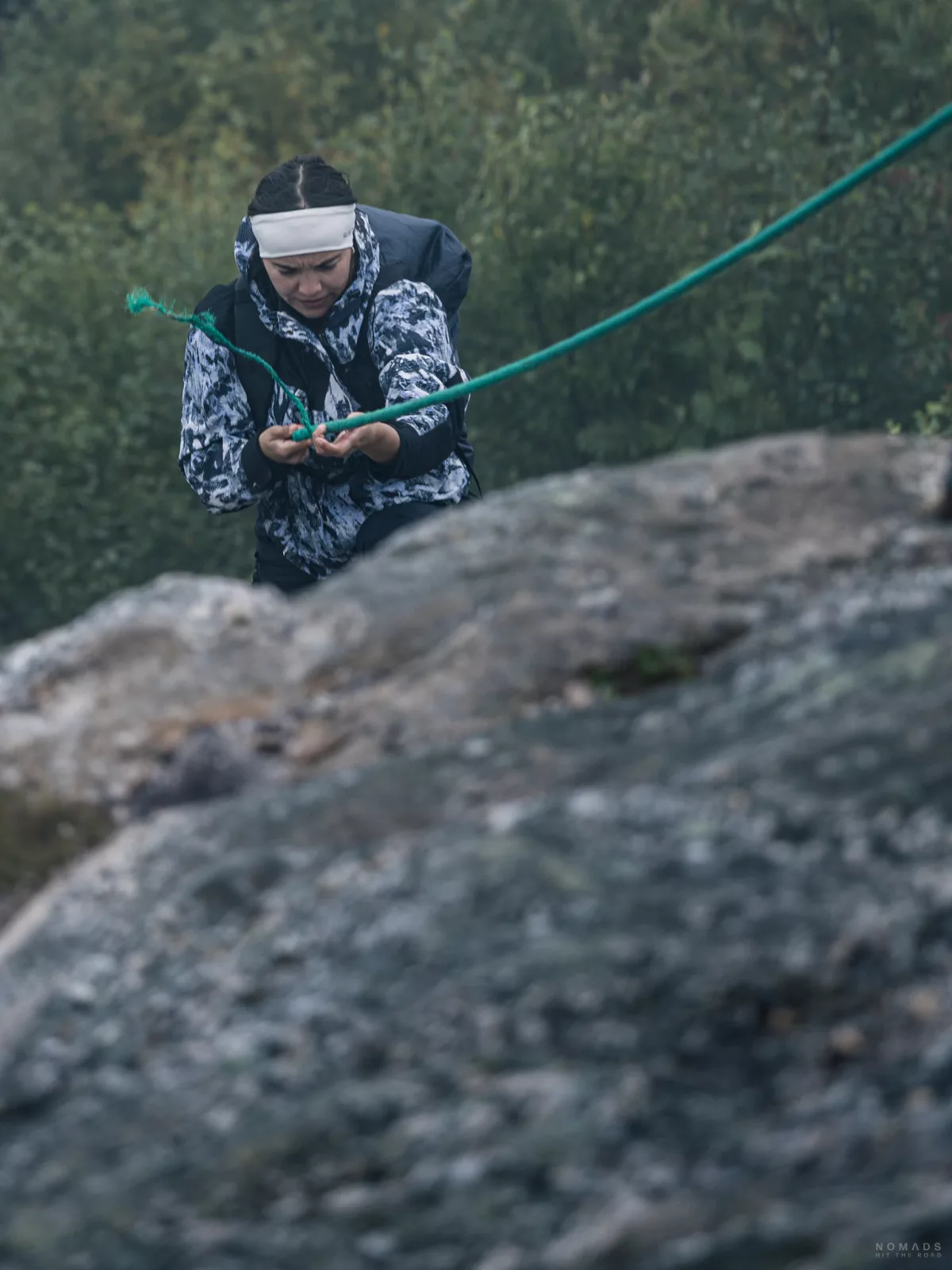 Frau zieht sich an einem Seil einen Felsen hoch