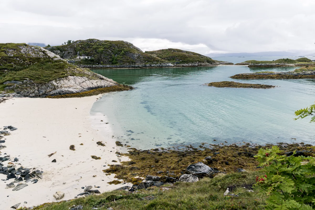 Blick auf eine kleine Bucht mit Sandstrand und blauem Meer