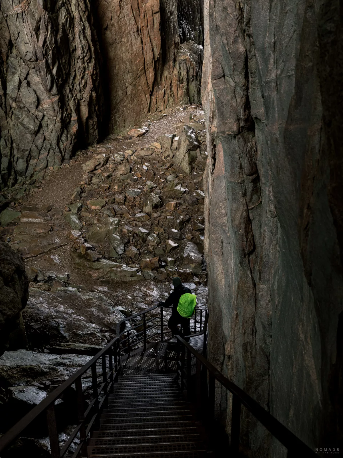 Person mit gelbem Rucksack läuft eine Treppe in einem Berg hinunter