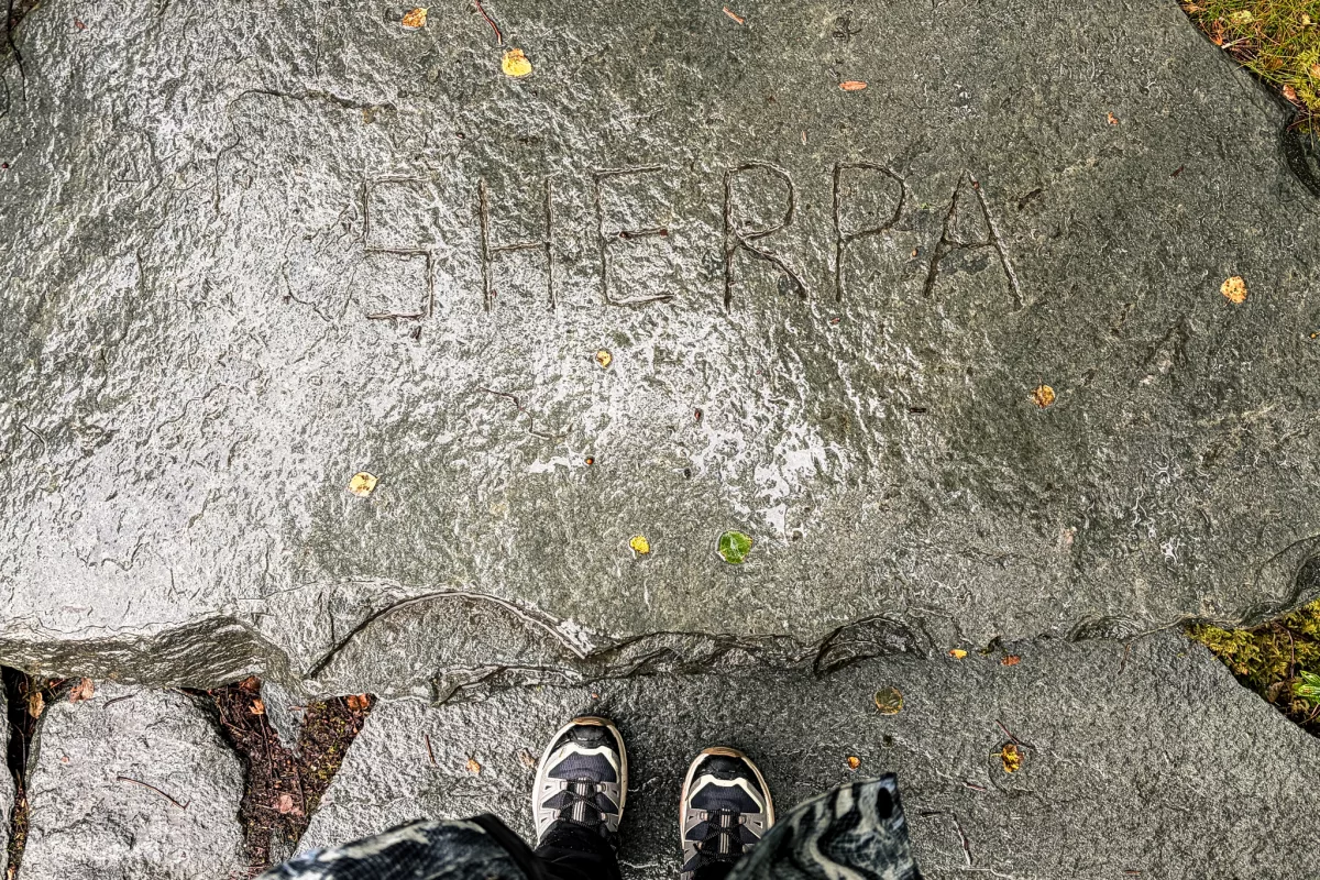 Sherpa eingraviert in den Felsen, Wanderschuhe unten im Bild zu sehen