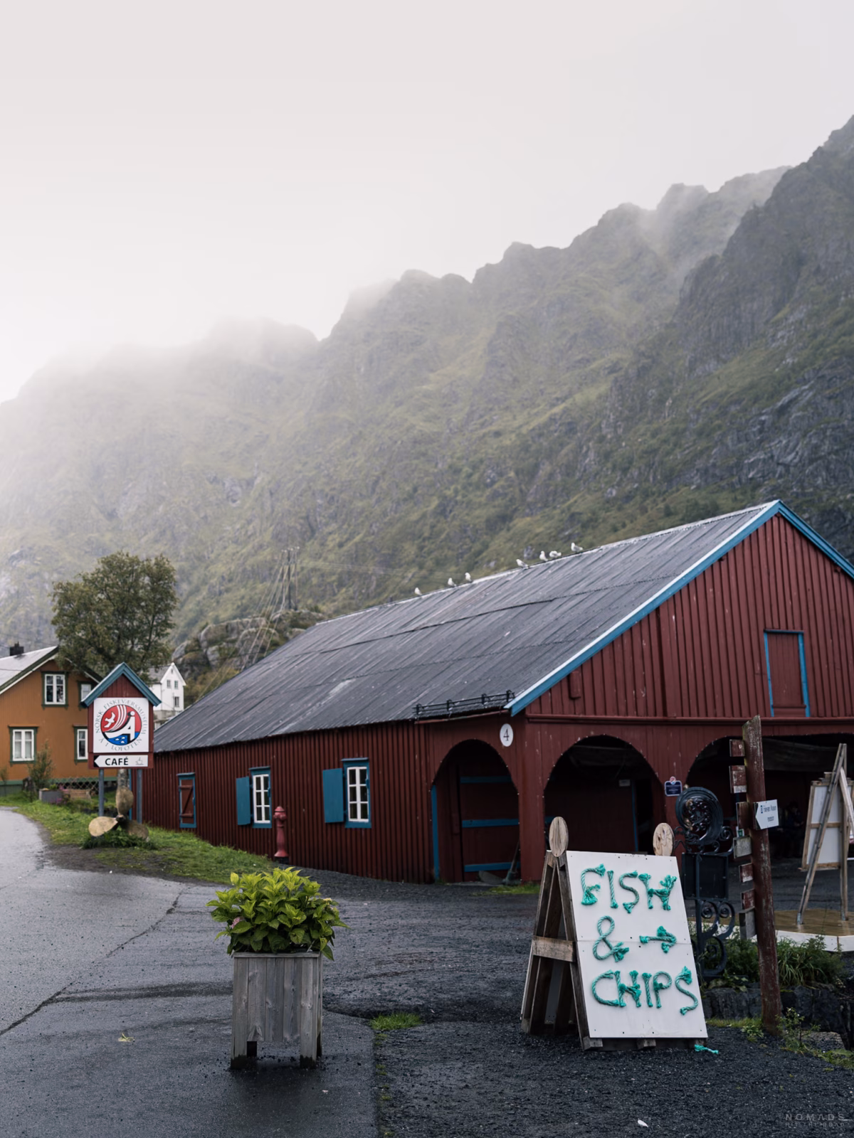 Rotes Rorbuer in Å i Lofoten mit einem Schild Fis & Chips davor