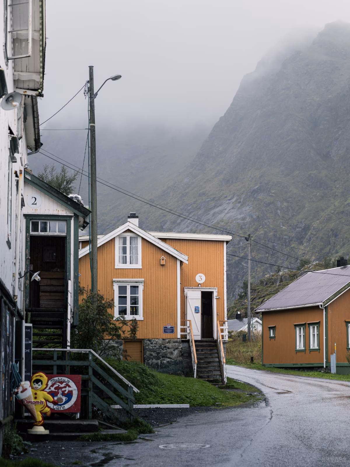 Gelbe Gebäude in einem Dorf vor vernebelten Bergen