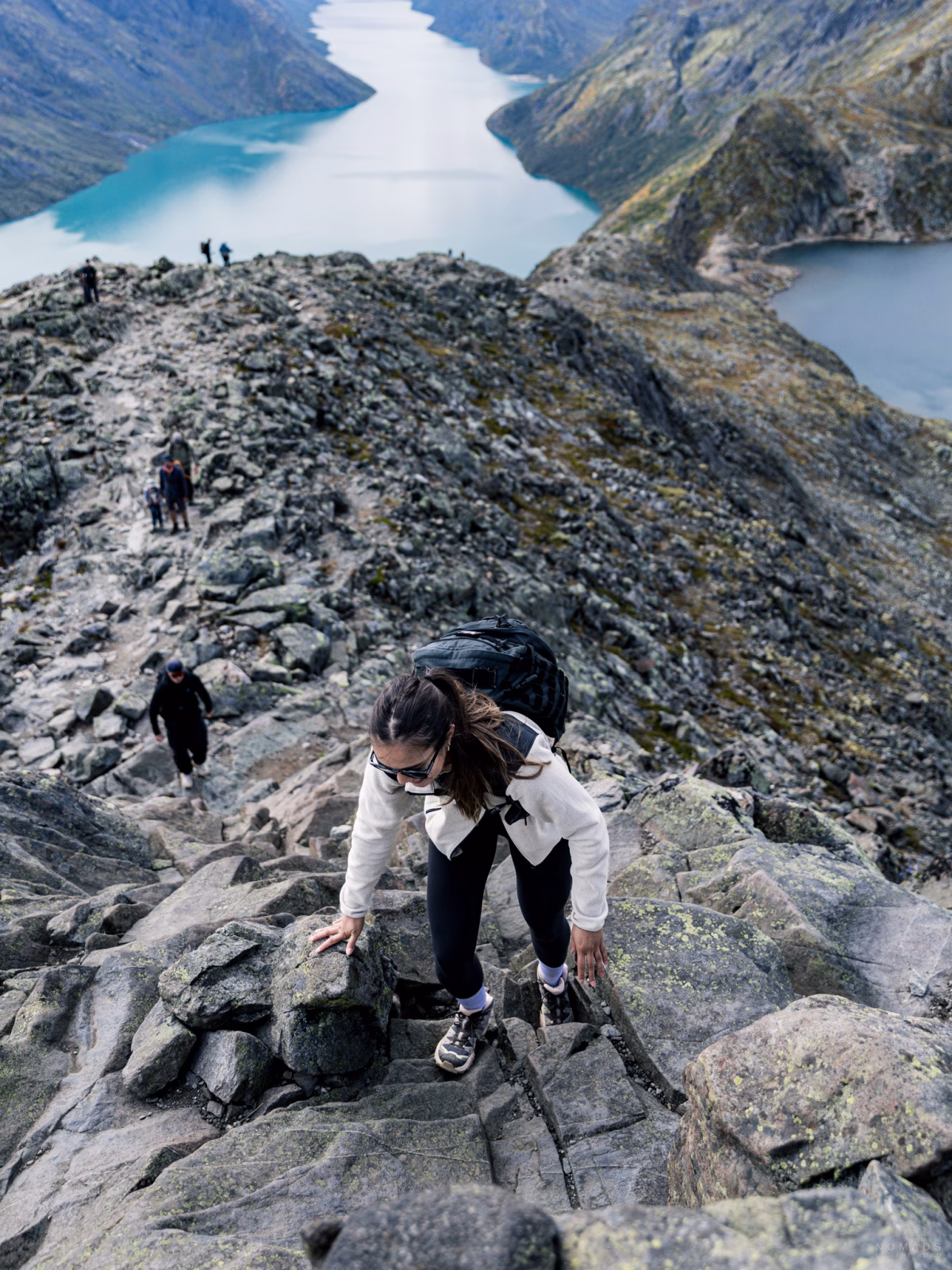 Frau kraxelt an Steinen hinauf zum Viewpoint des Besseggen in Norwegen
