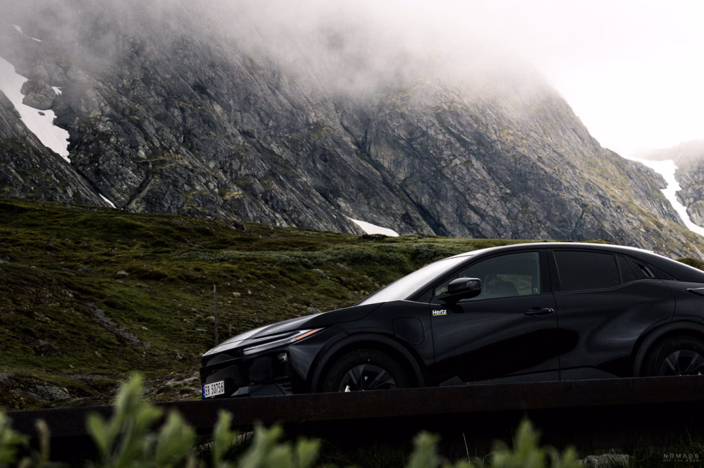 Schwarzer Mietwagen in Norwegen vor nebelverhangenen Bergen auf einer Passstraße
