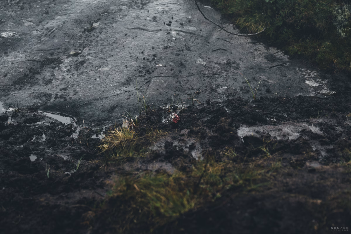 Rote Markierung eines Wanderweges auf einem Stein im Matsch