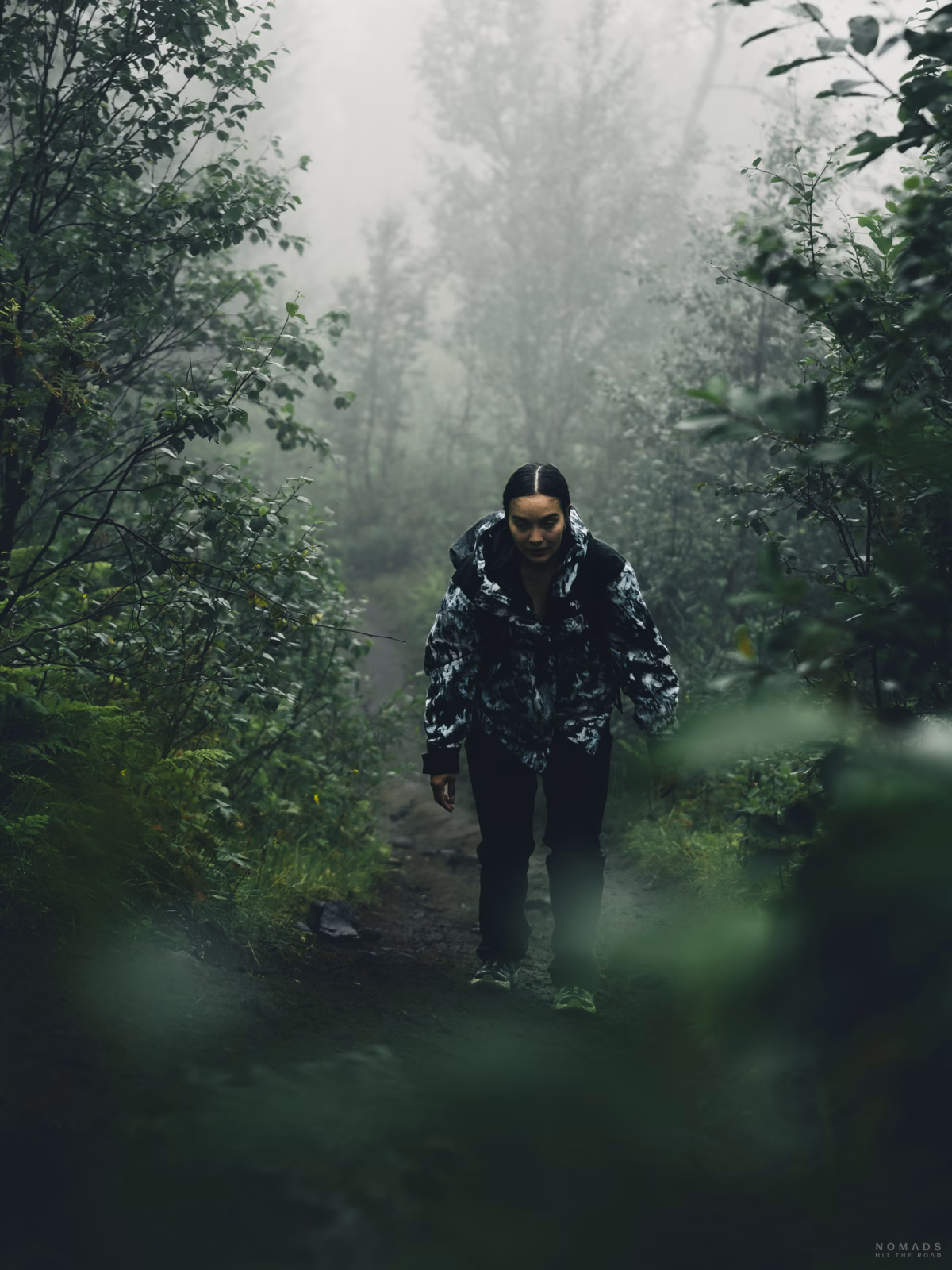 Frau läuft durch einen Wald mit grünen Bäumen und Büschen bei Nebel