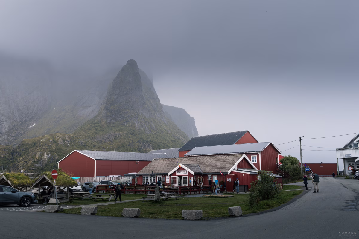 Blick auf das Taperiet Bistro in Reine mit grünem Vorplatz und Bergen im Hintergrund