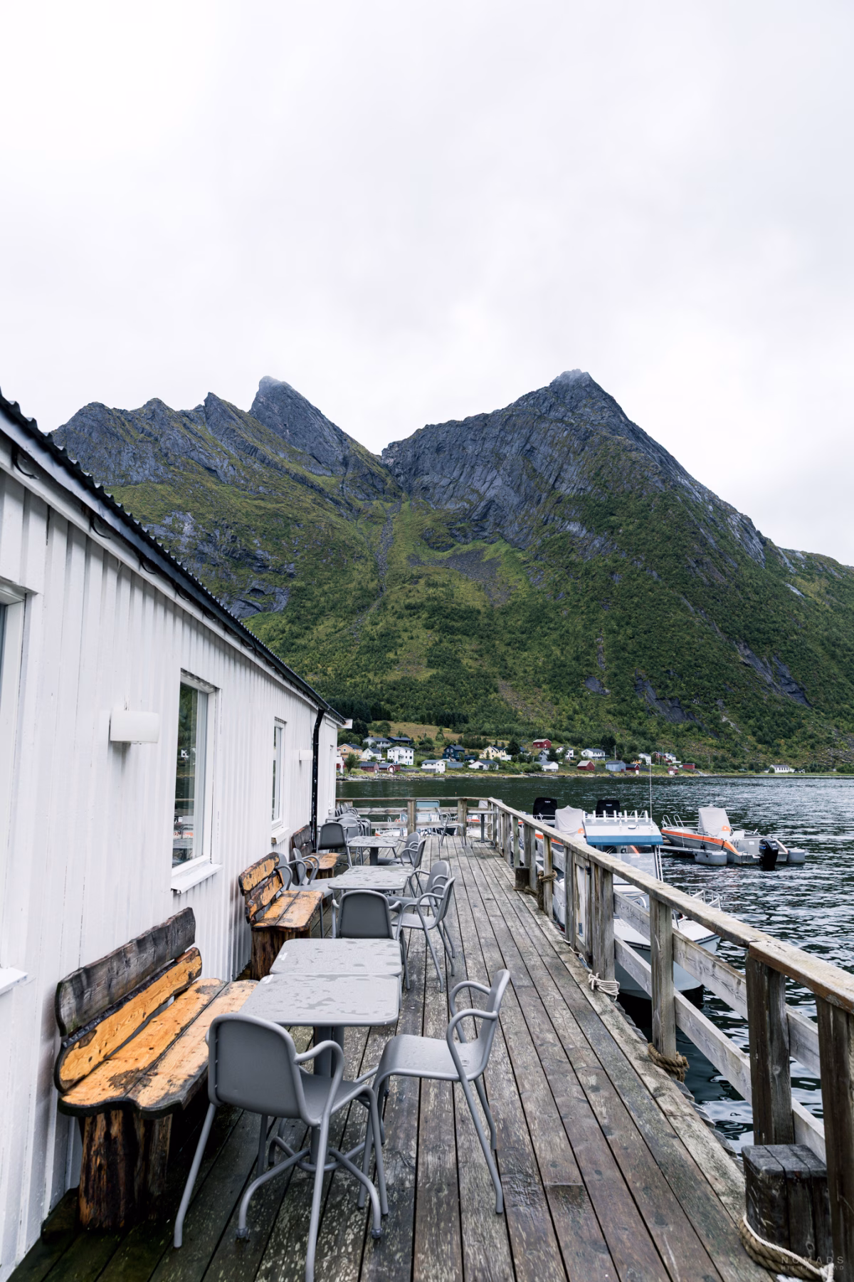 Terrasse mit Tischen und Stühlen am Fjord mit Blick auf Berge im The Fat Cod