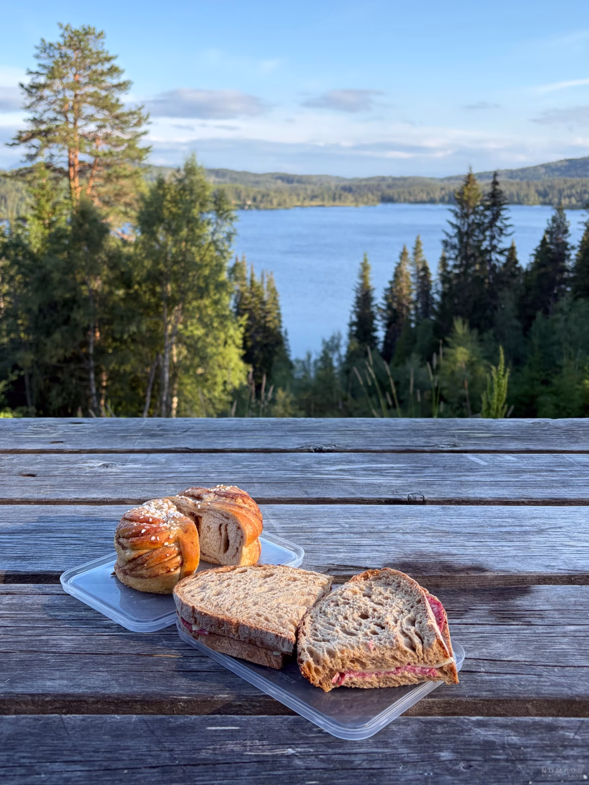 Stullen und Zimtschnecke auf einem Tisch mit Ausblick auf Wald und einen See in Norwegen